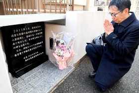 過労死した友人の人柄を語り、慰霊碑に手を合わせる堀恭平さん＝神戸市垂水区千代が丘２