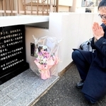 過労死した友人の人柄を語り、慰霊碑に手を合わせる堀恭平さん＝神戸市垂水区千代が丘２
