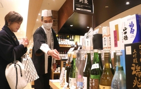 灘五郷の酒を試飲しながら選ぶ来場者（左）＝神戸阪急