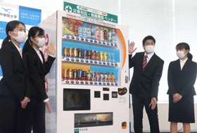 災害発生や市政の情報などを流す自動販売機をＰＲする学生たち＝神戸市中央区港島１、神戸学院大ポートアイランドキャンパス