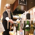 灘五郷の酒を試飲しながら選ぶ来場者（左）＝神戸阪急