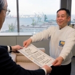 神戸新聞社の高梨柳太郎社長（左）から表彰状を受け取る「クリーンアップ関西事務局」共同代表の原賢治さん＝神戸市中央区東川崎町１