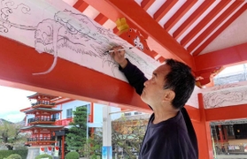 手水舎の内側に竜の下絵を描く山内章さん＝綱敷天満宮