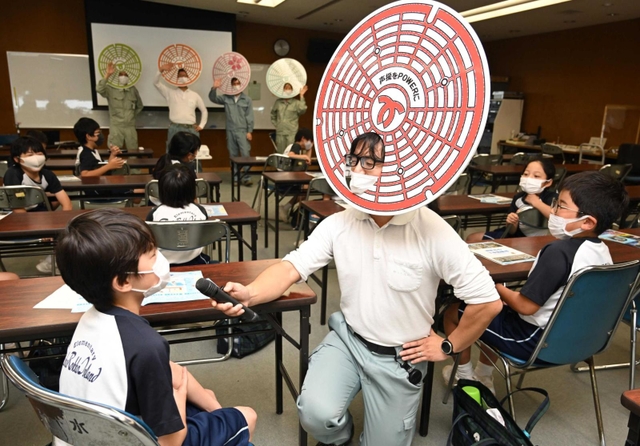 見学に来た小学生と交流するマンホールレンジャー＝神戸市東灘区魚崎南町２、東水環境センター