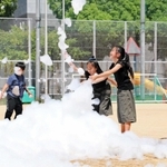 機械で降らせた「消えにくい泡」を触って遊ぶ児童たち＝神戸市中央区吾妻通４