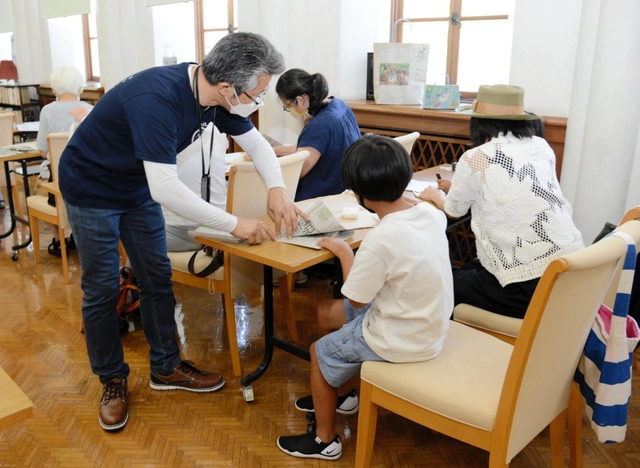 「かなしきデブ猫ちゃん」の連載紙面でバッグを作る参加者ら＝神戸市灘区王子町３