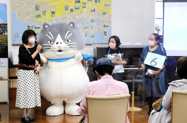 デブ猫「マル」から祝福を受ける潮崎孝代さん（左）ら＝神戸市灘区王子町３