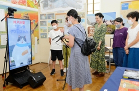 バーチャル映像で登場したマルとおしゃべりする参加者＝神戸文学館