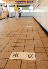 ＪＲ住吉駅につながる連絡通路の床に記された「東京」の駅名表示。奧に「横浜」「国府津」と続く＝ＪＲ住吉駅前