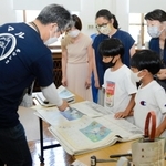 「かなしきデブ猫ちゃん」の連載紙面でバッグを作る参加者ら＝神戸市灘区王子町３