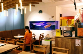食事もできる１階のカフェスペース。大きなアロワナがゆったり泳ぐ水槽も＝神戸市東灘区甲南町３