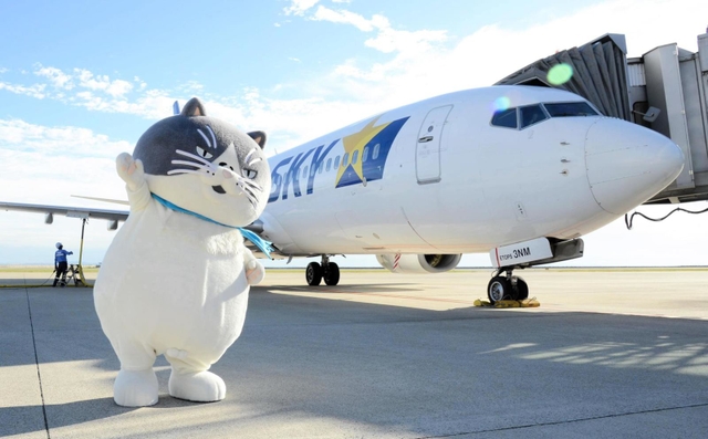 スカイマークの機体をバックに手を振るマル＝神戸空港