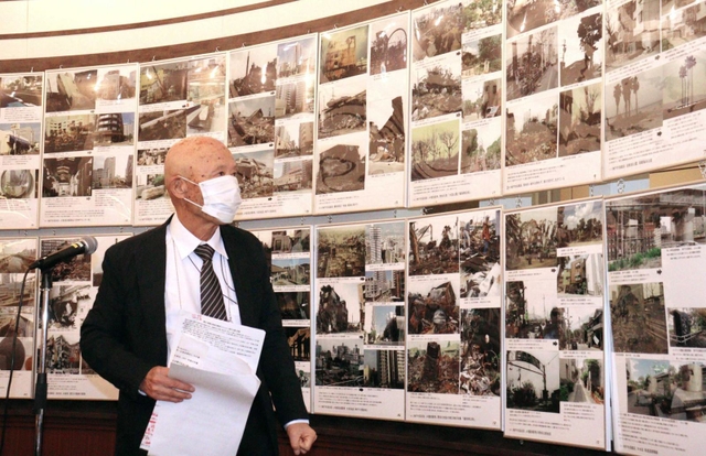 阪神・淡路大震災直後と復興後の写真を対比し、震災遺構保存の大切さを訴える三原泰治さん＝神戸市長田区腕塚町５