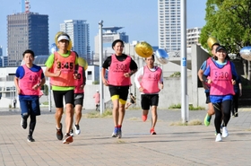 目標タイムが示されたビブスや風船の感覚を確かめながら走る神戸マランソンのペースセッター＝神戸市中央区脇浜海岸通１