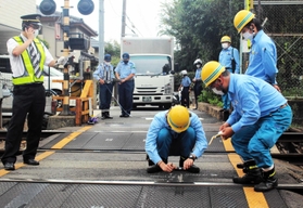 トラックが立ち往生した踏切を調べる阪急電鉄の職員ら＝６日午前、神戸市東灘区本山北町２