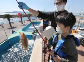 水槽から魚を釣り上げた利用客。明石海峡を眺めながら開放感のある釣りが楽しめる＝神戸市垂水区海岸通、マリンピア神戸さかなの学校