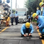 トラックが立ち往生した踏切を調べる阪急電鉄の職員ら＝６日午前、神戸市東灘区本山北町２