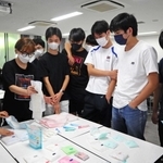 多種類の生理用品が並ぶ。「買ってきてと言われたらどれがいいのかな」と、灘高生に問いかける甲南女子大生＝神戸市東灘区、灘高校