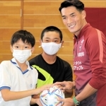 贈ったボールを手に児童らと記念写真に納まる槙野智章選手（右）＝宮川小学校