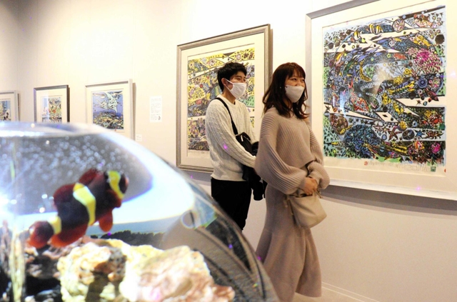 沖縄の海や魚を描いた木版画と水槽を遊泳する魚のコラボレーションが楽しめる企画展＝アトア