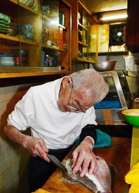 「握力は１２。小学生くらいや」。冗談を言いながらも包丁を持つと目つきが変わる＝神戸市中央区楠町６、鮨いずも（撮影・坂井萌香）