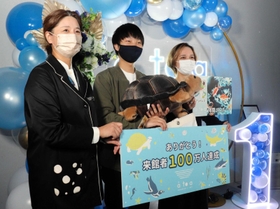 １００万人目の来館者に記念品を贈る中山寛美館長（左端）＝アトア