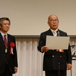 同窓会創立５０周年記念式典で辻正次学長から感謝状を受け取り、あいさつする同窓会の山本顕一会長（右）＝神戸ベイシェラトン＆タワーズ