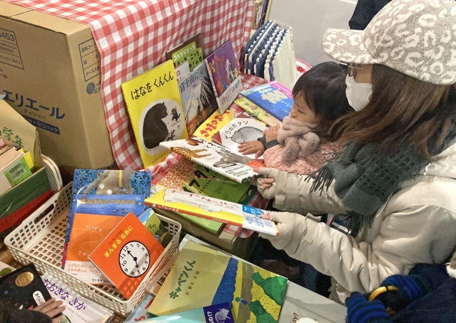 「ブックサンタ」から贈られた絵本を選ぶ女児＝神戸市北区南五葉１、インクルひろば
