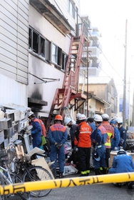 夜が明け、現場を調べる消防隊員ら＝神戸市長田区