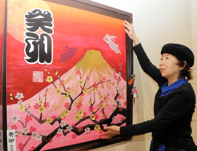 全壊した実家の最寄り駅で、新作の書を額に飾り付ける野原神川さん＝ＪＲ摂津本山駅