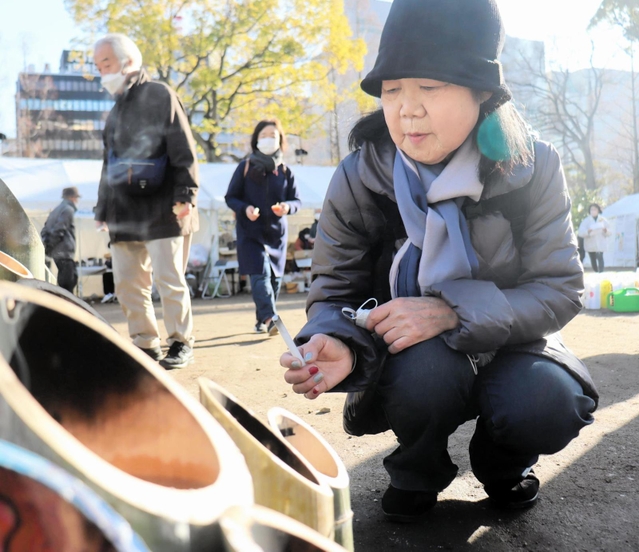 亡き弟を思って竹灯籠に火をともす豊島美貴子さん＝１７日午前９時９分、東遊園地