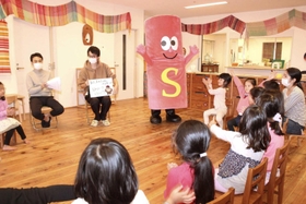 子どもに脳卒中について説明する（左から）尾原信行医師、藤原悟医師、ストローくん＝神戸市中央区港島南町２、杉の子保育園