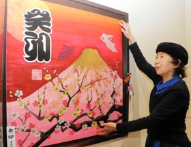全壊した実家の最寄り駅で、新作の書を額に飾り付ける野原神川さん＝ＪＲ摂津本山駅