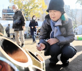 亡き弟を思って竹灯籠に火をともす豊島美貴子さん＝１７日午前９時９分、東遊園地