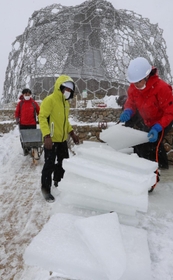 雪が降りしきる中、氷棚でできた天然の氷を切り出す職員ら＝２７日午前、神戸市灘区六甲山町、自然体感展望台「六甲枝垂れ」