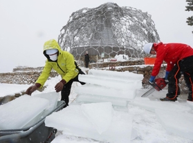 雪が降りしきる中、氷棚でできた天然の氷を切り出す職員ら＝２７日午前、神戸市灘区六甲山町、自然体感展望台「六甲枝垂れ」