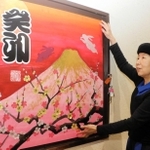 全壊した実家の最寄り駅で、新作の書を額に飾り付ける野原神川さん＝ＪＲ摂津本山駅