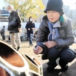 亡き弟を思って竹灯籠に火をともす豊島美貴子さん＝１７日午前９時９分、東遊園地