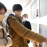 母、祖母と一緒に亡き祖父の名を確かめる松端泰久さん（中央）＝１７日午前１１時２１分、中央区加納町６