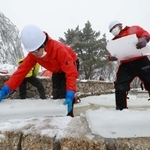 雪が降りしきる中、氷棚でできた天然の氷を切り出す職員ら＝２７日午前、神戸市灘区六甲山町、自然体感展望台「六甲枝垂れ」