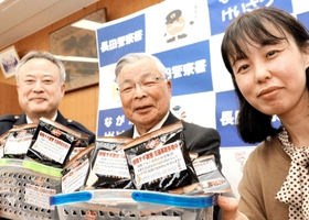 啓発標語を記した商品を贈った吉田ピーナツ食品の吉田泰弘会長（中央）と商品企画部の松本亜衣子係長（右）＝長田署