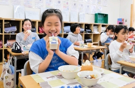 マルのイラストが掲載された牛乳を飲む児童たち＝灘の浜小学校