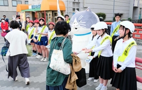 西代中、宮川小の生徒児童らと啓発グッズを配るマル（中央）＝長田神社前商店街