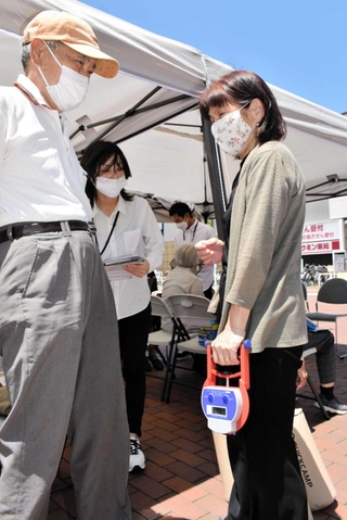 握力などを測定して転倒リスクをチェックしてもらう夫婦＝ＪＲ兵庫駅前