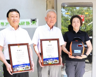 ＡＥＤを寄贈した神防社の担当者（右）に感謝状を贈った神戸愛山協会の吉野宏会長（中央）ら＝神戸市灘区王子町２