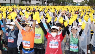 スタート前、黄色い手袋をはめ一斉に手を振るランナー＝神戸市中央区