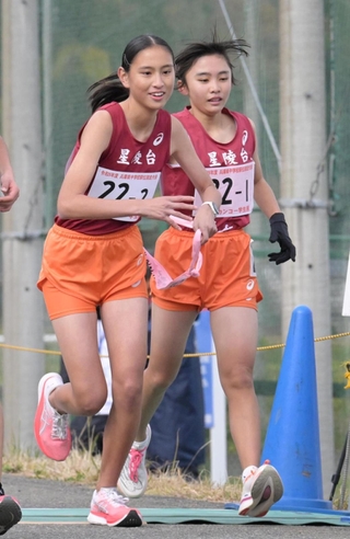 女子・星陵台の１区髙石愛尋選手（右）からたすきを受け取る２区石田礼衣選手＝豊岡市日高町（撮影・斎藤雅志）