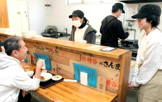 カウンターの客と会話を楽しむ留学生ら＝兵庫区東山町２