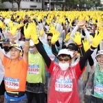 スタート前、黄色い手袋をはめ一斉に手を振るランナー＝神戸市中央区