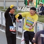 ゲストランナーの金哲彦さん（左）に手を引かれて制限時間ぎりぎりにゴールした寺西司さん＝１９日午後、神戸市中央区港島中町６（撮影・笠原次郎）